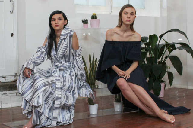 Two women are seated in a minimalist, plant-filled room